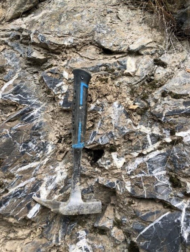 Quartz-carbonate stockwork veining in outcrop at the Monte copper-gold project near Cajnice, shown with a rock hammer for scale